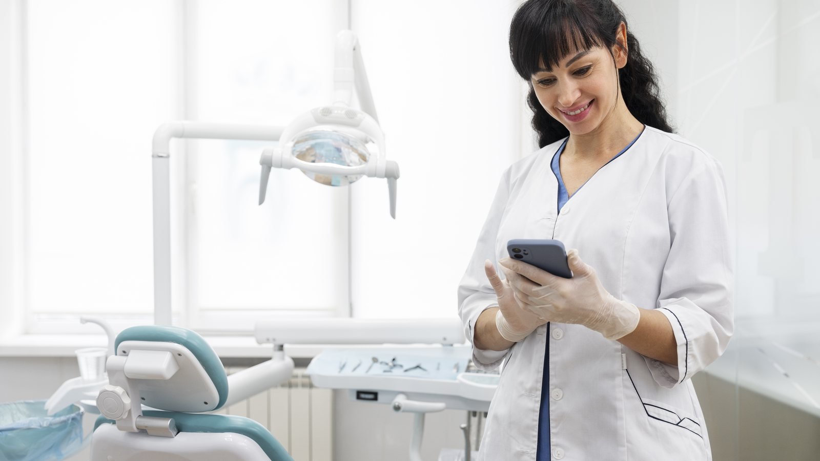 Dentist using a smartphone in a treatment room, a reminder to check your dental practice website on mobile